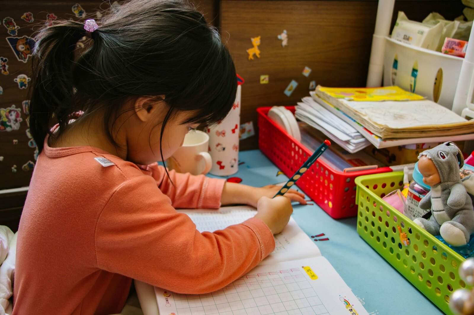 Child writing at a desk with pencil and paper